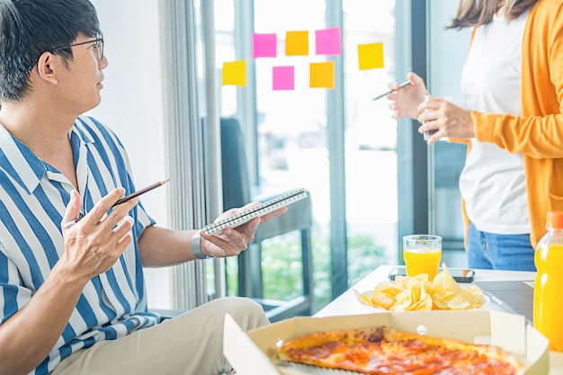 Amici che parlano e mangiano pizza nella sala riunioni.