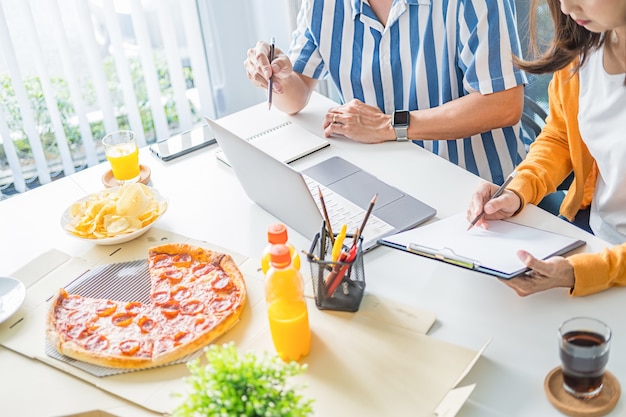 Amici che parlano e mangiano pizza nella sala riunioni.