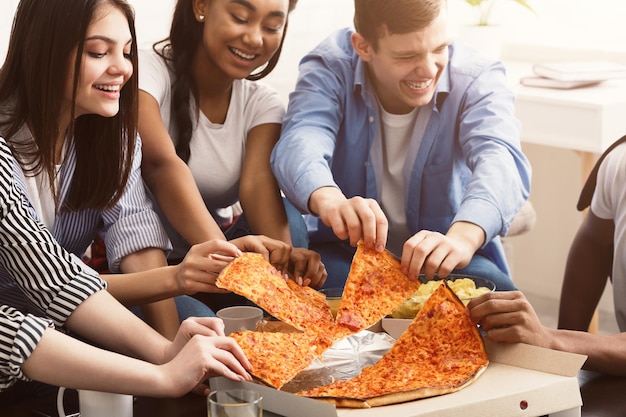 Amici che prendono fette di pizza calda da una scatola di cartone