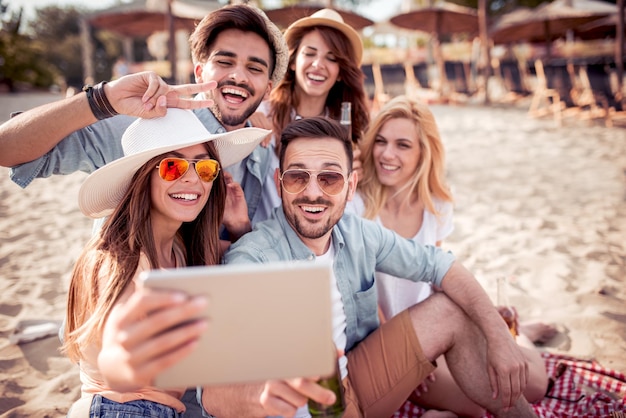 Amici che prendono selfie insieme sullo smartphone sulla spiaggia