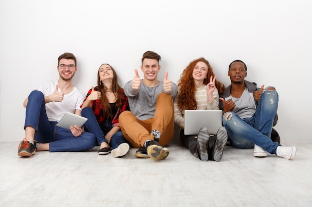 Amici che ridono felici, studenti diversi che trascorrono del tempo insieme in casa. Sfondo bianco, copia spazio