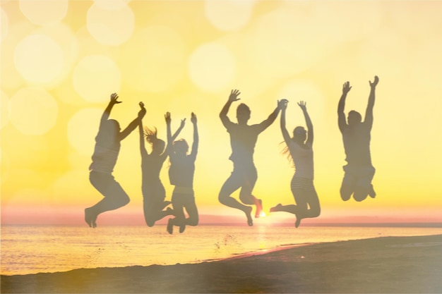 Amici che saltano sulla spiaggia al tramonto