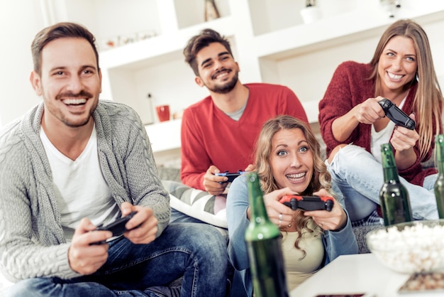 Amici che si divertono sul divano con i videogiochi