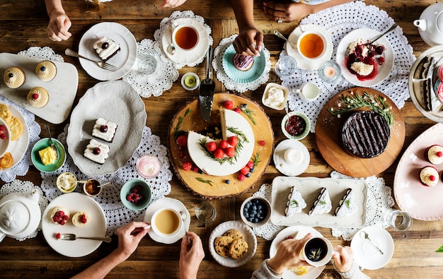 Amici che si riuniscono insieme su Tea Party Eating Cakes Enjoyment happiness