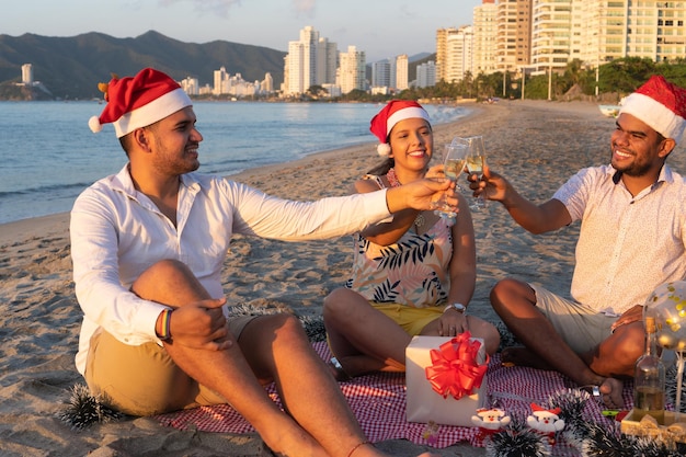 Amici che sorridono e propongono un brindisi mentre si siedono a festeggiare il nuovo anno sulla spiaggia.