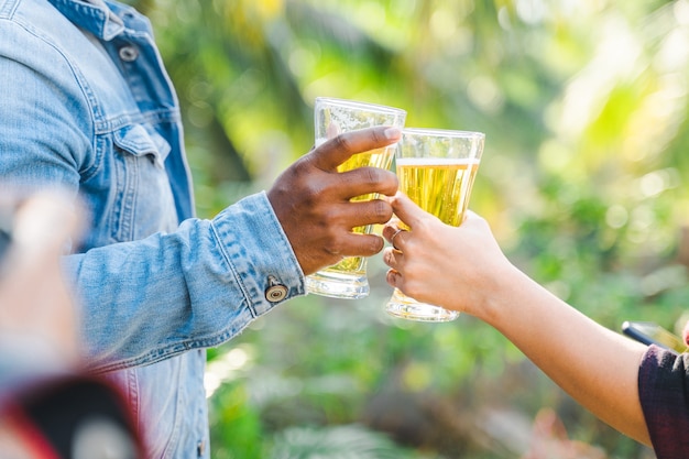 Amici che tintinnano bottiglia di birra durante il campeggio all'aperto