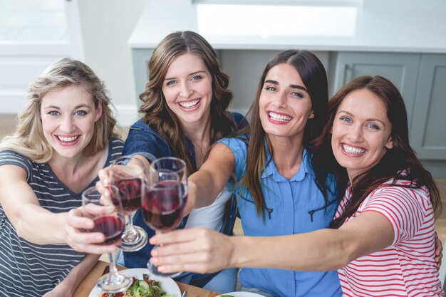 Amici che tostano bicchiere di vino mentre mangiano