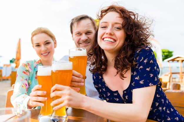 Amici che tostano con la birra nel ristorante del giardino