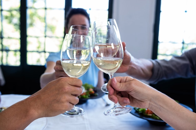 Amici che tostano il bicchiere di vino mentre pranzano