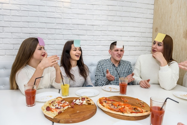 Amici con adesivi sulla fronte che giocano a Indovina chi al bar