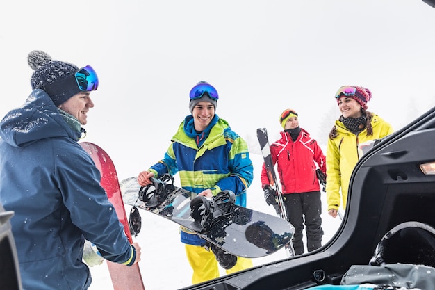 Amici con sci e snowboard che scaricano roba dalla macchina