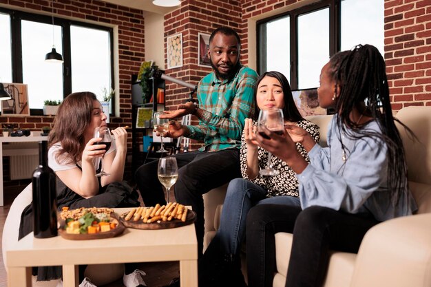 Amici culturalmente diversi che parlano, conversano tra loro, bevono vino, mangiano, assaggiano formaggi, grissini in riunioni di persone diverse. Compagni di nazionalità diverse che si godono la vita sociale.