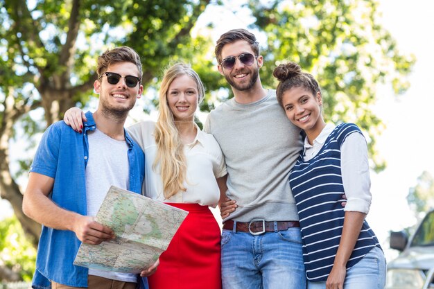 Amici dell&#39;anca che tengono mappa e sorridendo alla telecamera sulla strada