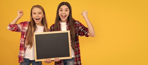 Amici delle ragazze della scuola bambini felici nella lavagna della scuola della tenuta a scacchi casual per lo spazio della copia