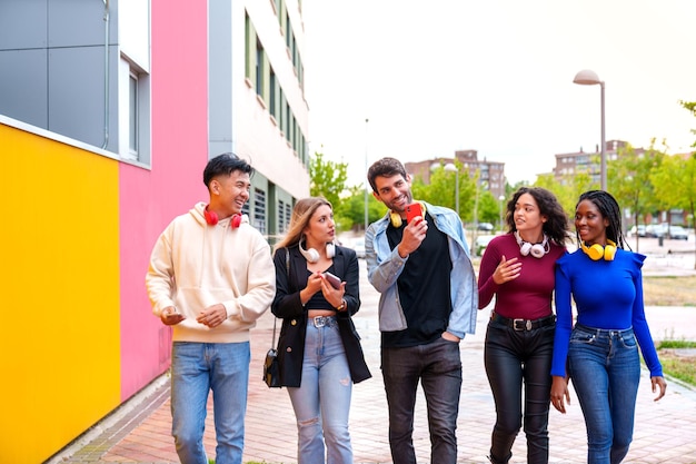 amici di diverse etnie che catturano la vibrante strada della città al tramonto con i telefoni cellulari