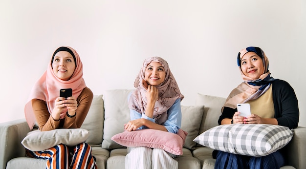 Amici di donne islamiche utilizzando smart phone e alzando lo sguardo