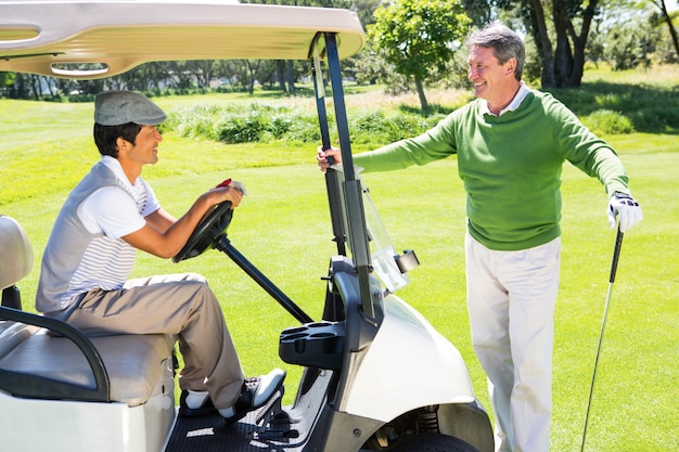 Amici di golf felici per la giornata in buggy