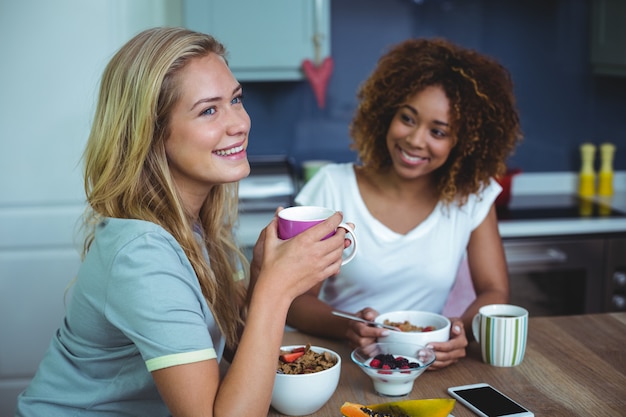 Amici di sesso femminile facendo colazione al tavolo in cucina