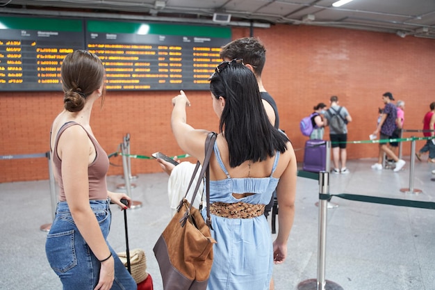 Amici di viaggio che guardano le informazioni sul pannello informativo del volo o del treno a lunga percorrenza