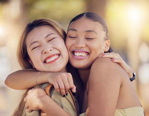 Amici donne e abbraccio per amore cura e sostegno mentre si è all'aperto per viaggiare felicità e legame con donna asiatica e nera Coppia lesbica con un sorriso nella natura per la pace estate e tempo insieme