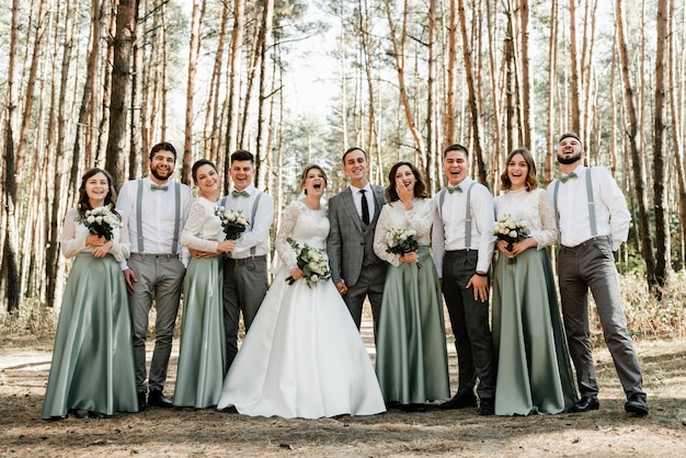 Amici e amicizia al matrimonio, ragazzi e ragazze con gli sposini nel bosco, foto di gruppo del matrimonio, giorno delle nozze dello sposo con la sposa, allegra compagnia di amici per gli sposini