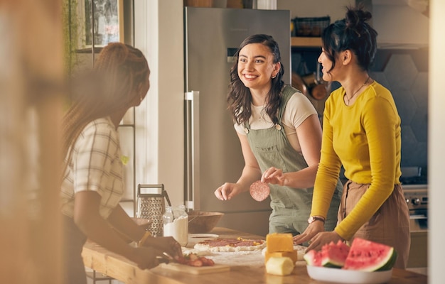 Amici e donne felici che cucinano la pizza in cucina, si uniscono e si divertono insieme a casa Sorridono ragazze e cuociono margherita e salame a pranzo, formaggio su carne e anguria al brunch