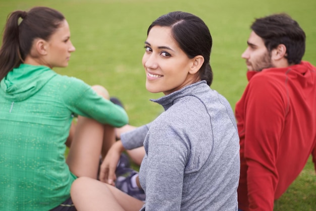 Amici e fitness Ritratto di giovani in abbigliamento sportivo seduti su un campo sportivo erboso