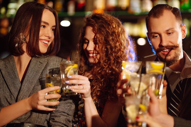 Amici felici che applaudono e bevono cocktail godendosi la festa nel club Concetto di stile di vita giovanile