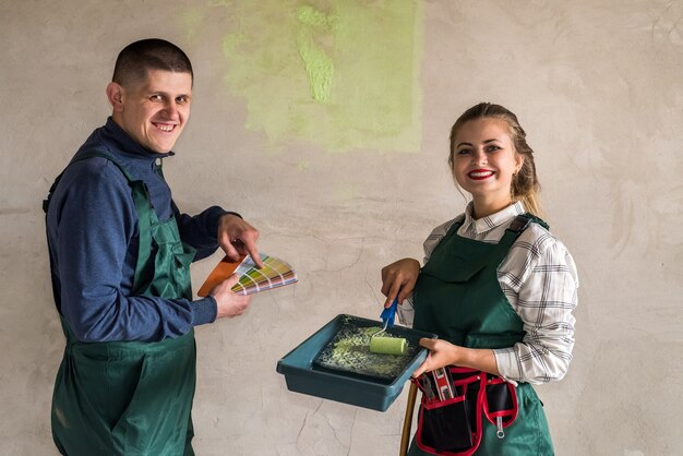 Amici felici che dipingono le pareti di colore verde