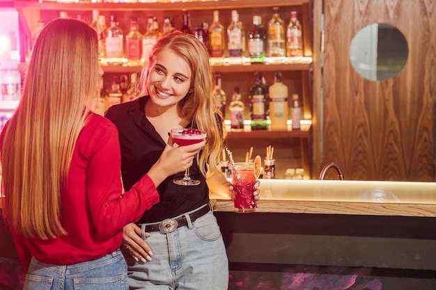 Amici felici che fanno il tifo e bevono cocktail alla festa in spiaggia all'aperto I giovani millennial si divertono durante la notte estiva del fine settimana Stile di vita giovanile e concetto di vita notturna Focus principale sui ragazzi di sinistra