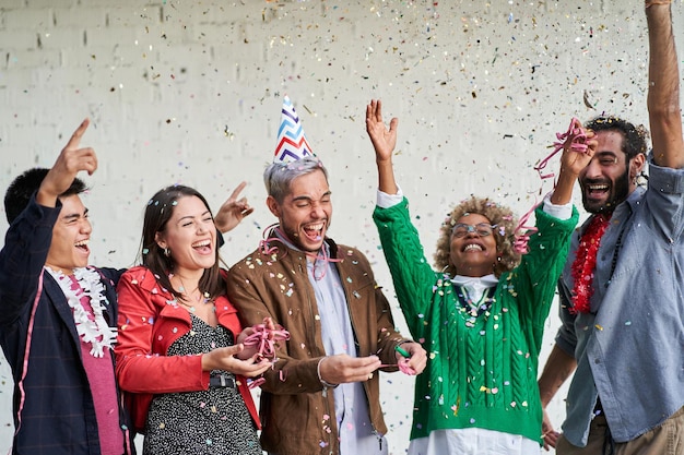 Amici felici che festeggiano con i coriandoli insieme divertendosi