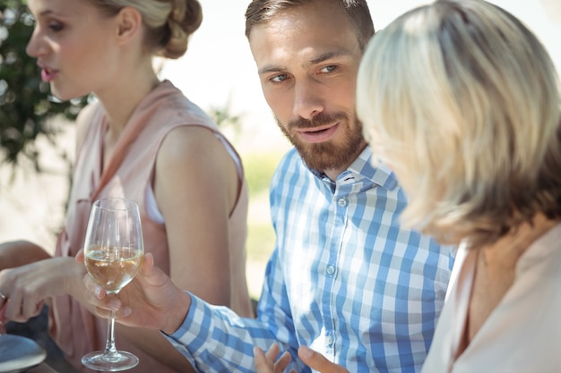 Amici felici che interagiscono pur avendo un bicchiere di vino