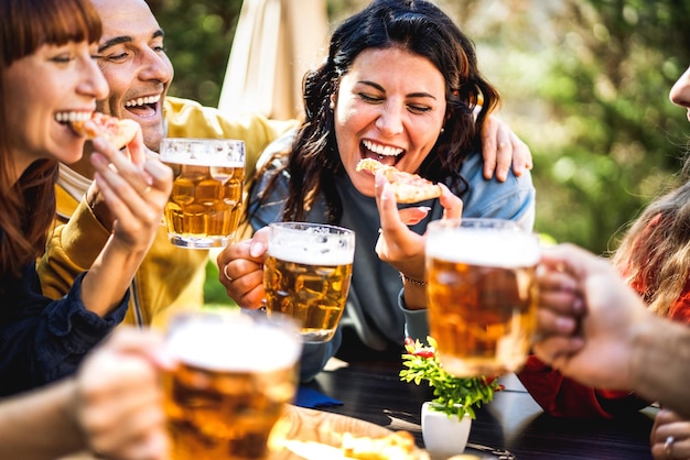 Amici felici che mangiano pizza alla birreria all'aperto