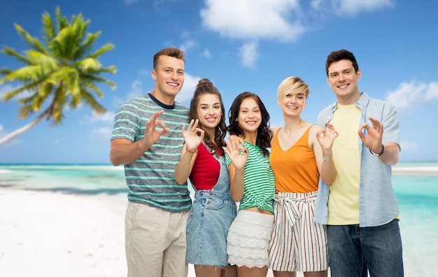 amici felici che mostrano ok sullo sfondo della spiaggia