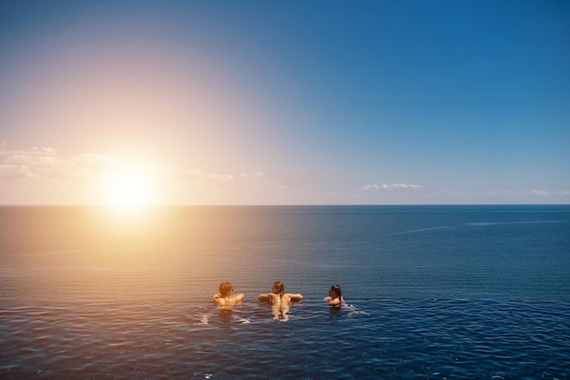 Amici felici che nuotano nella piscina a sfioro contro il lungomare