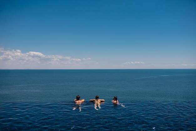 Amici felici che nuotano nella piscina a sfioro contro il lungomare