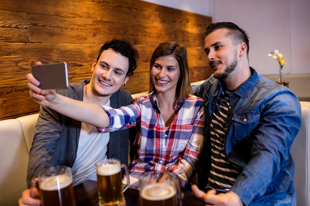 Amici felici che prendono selfie al ristorante