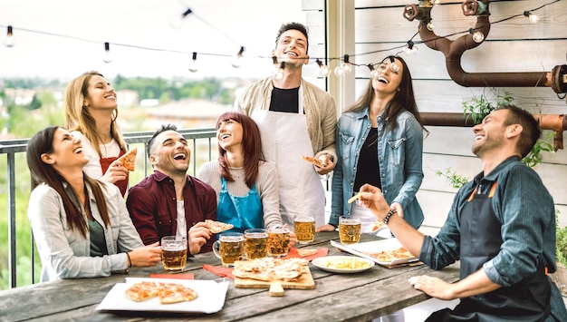 Amici felici che si divertono a mangiare la pizza sul balcone a cena in casa