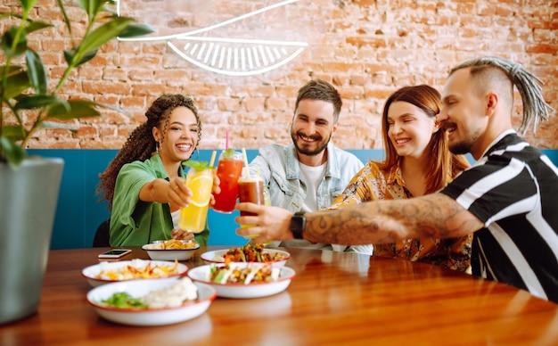 Amici felici che si divertono al bar Giovani seduti in un ristorante che si divertono insieme