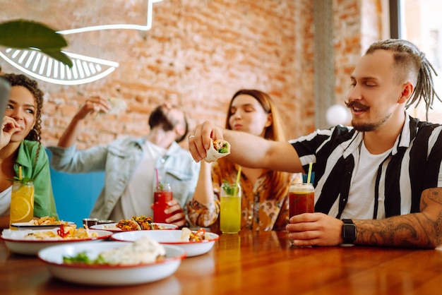 Amici felici che si divertono al bar Giovani seduti in un ristorante che si divertono insieme