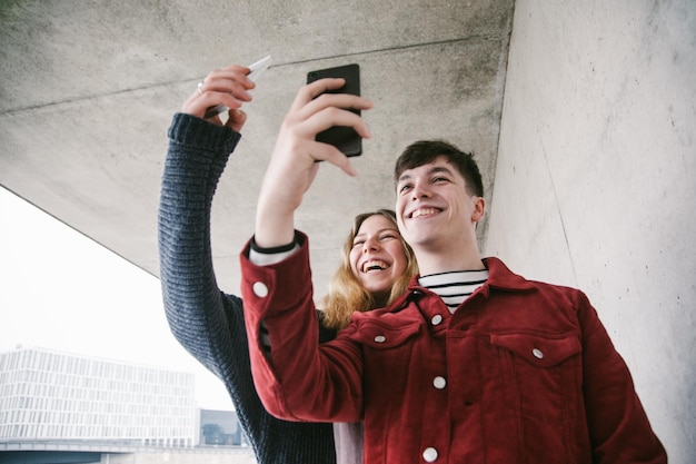 Amici felici che si fanno un selfie contro il muro.