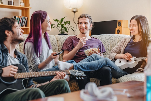 Amici felici che suonano su strumenti musicali divertendosi nel soggiorno di casa