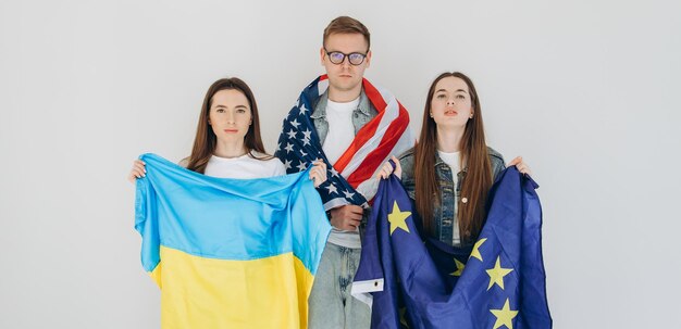 Amici felici che tengono bandiera Ucraina USA e UE