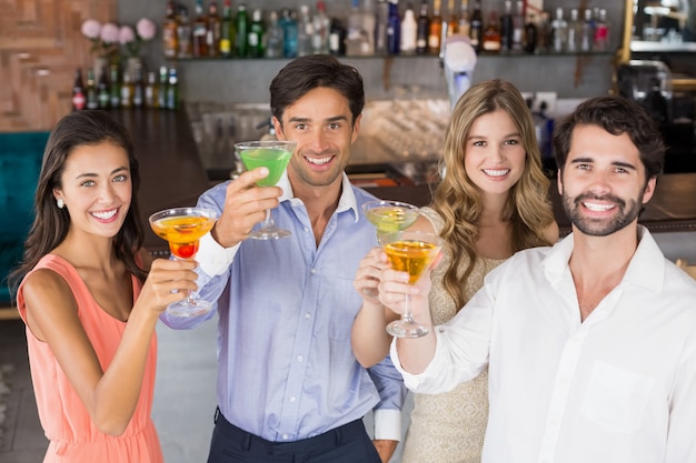 Amici felici che tostano bicchieri da cocktail