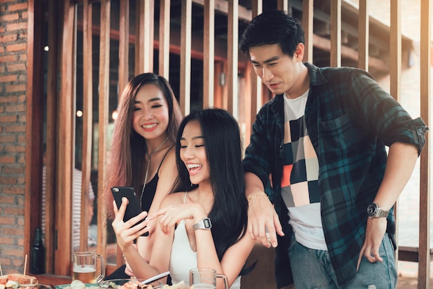 Amici felici che usano lo smartphone in un ristorante