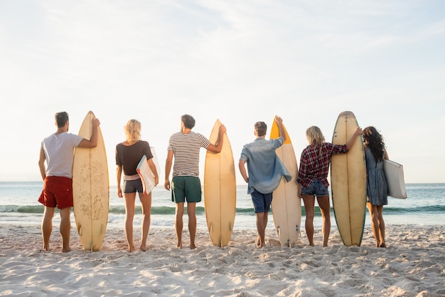 Amici felici in fila con le tavole da surf