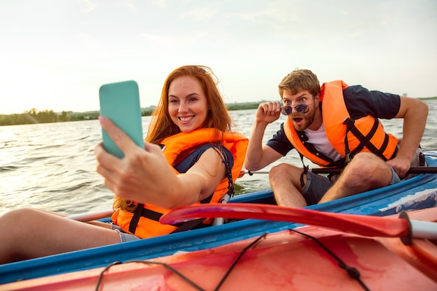 Amici felici in kayak sul fiume con il tramonto sullo sfondo