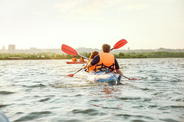 Amici felici in kayak sul fiume con il tramonto sullo sfondo