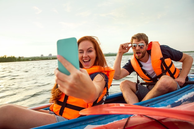 Amici felici in kayak sul fiume con il tramonto sullo sfondo