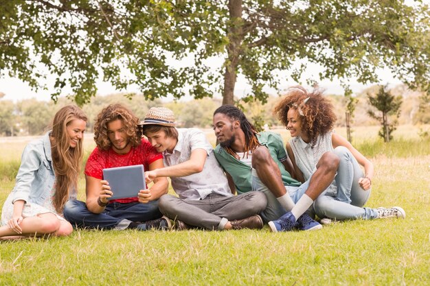 Amici felici nel parco guardando tablet